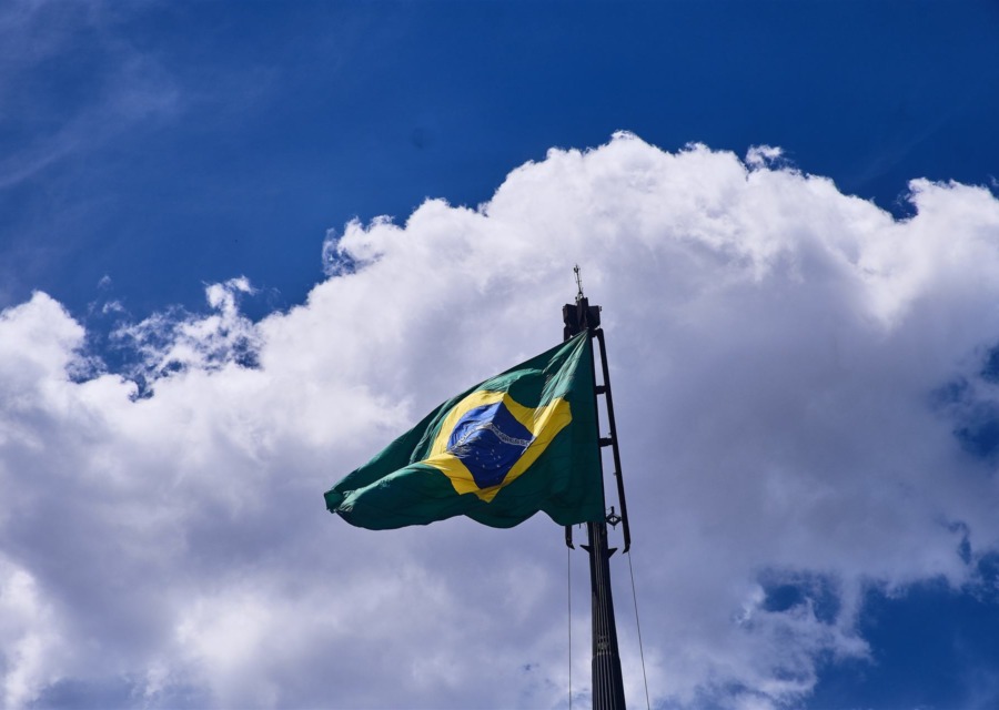 Bandeira do Brasil tremulando contra céu azul com nuvens