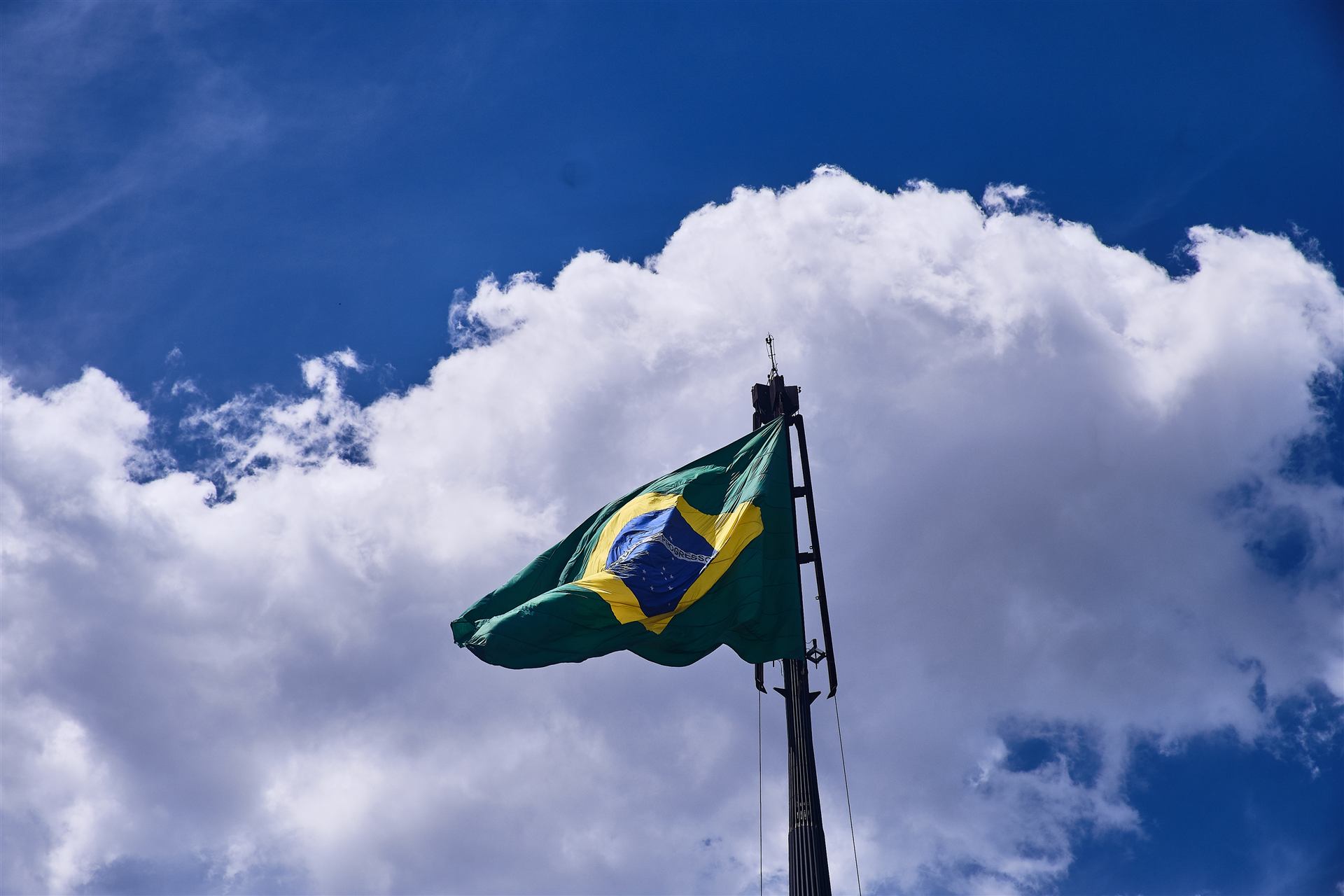 Bandeira do Brasil tremulando contra céu azul com nuvens