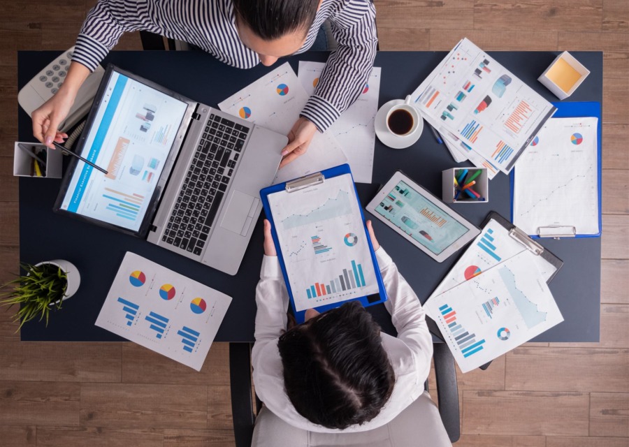 Vista de cima de duas pessoas analisando gráficos e relatórios